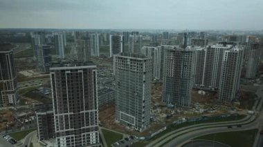 Modern çok katlı binaların yapımı. Yeni bir şehir bloğu inşaatı. İnşaat halindeki binalar ve kule vinçleri. Bulutlu havada hava fotoğrafçılığı.