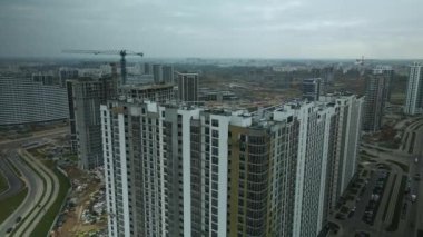 Modern çok katlı binaların yapımı. Yeni bir şehir bloğu inşaatı. İnşaat halindeki binalar ve kule vinçleri. Bulutlu havada hava fotoğrafçılığı.
