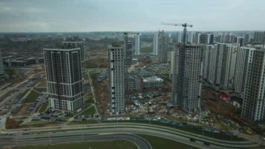 Modern çok katlı binaların yapımı. Yeni bir şehir bloğu inşaatı. İnşaat halindeki binalar ve kule vinçleri. Bulutlu havada hava fotoğrafçılığı.