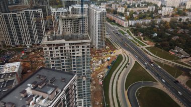 Modern çok katlı binaların yapımı. Yeni bir şehir bloğu inşaatı. İnşaat halindeki binalar ve kule vinçleri. Bulutlu havada hava fotoğrafçılığı.