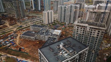 Modern çok katlı binaların yapımı. Yeni bir şehir bloğu inşaatı. İnşaat halindeki binalar ve kule vinçleri. Bulutlu havada hava fotoğrafçılığı.