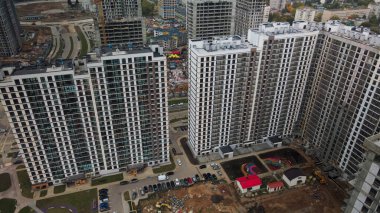 Modern çok katlı binaların yapımı. Yeni bir şehir bloğu inşaatı. İnşaat halindeki binalar ve kule vinçleri. Bulutlu havada hava fotoğrafçılığı.