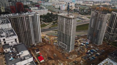 Modern çok katlı binaların yapımı. Yeni bir şehir bloğu inşaatı. İnşaat halindeki binalar ve kule vinçleri. Bulutlu havada hava fotoğrafçılığı.