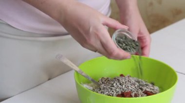 Yeşil karabuğdaydan ekmek yapmak. Bir kadın yeşil karabuğday hamuruna keten, ayçiçeği ve balkabağı tohumu ekler. Hamuru kaşıkla karıştırmaya başlıyor. Yakın çekim..
