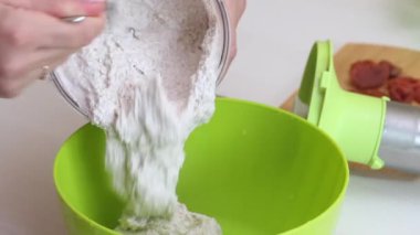 Yeşil karabuğdaydan ekmek yapmak. Bir kadın blender kasesinden toprak yeşili karabuğdayı bir konteynıra aktarıyor. Yakın çekim..