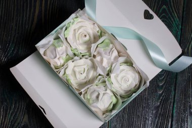 Hediye kutusunda ev yapımı marşmelov. Zephyr gülleri. Şekerleme gülleri. Siyah çam tahtalarında. Yakın çekim..