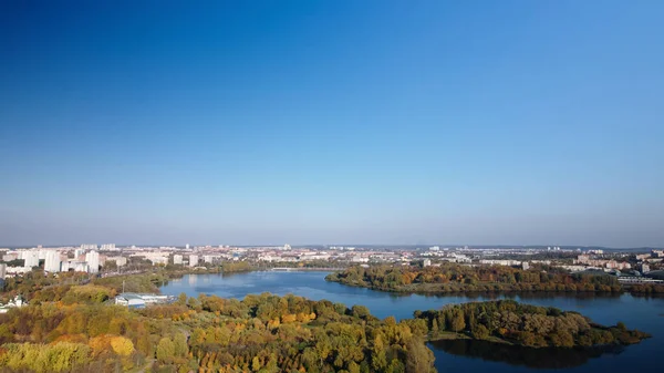 飞越秋天的公园 秋天黄叶的树是可见的 地平线上有蓝天和城市的房屋 公园的河流清晰可见 空中摄影 — 图库照片