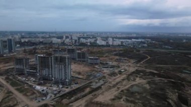 Modern çok katlı binaların yapımı. Yeni bir şehir bloğu inşaatı. İnşaat halindeki binalar ve kule vinçleri. Bulutlu havada hava fotoğrafçılığı.
