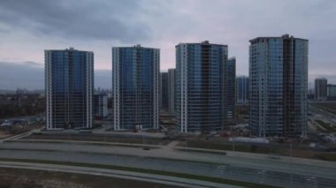Modern çok katlı binaların yapımı. Yeni bir şehir bloğu inşaatı. İnşaat halindeki binalar ve kule vinçleri. Bulutlu havada hava fotoğrafçılığı.