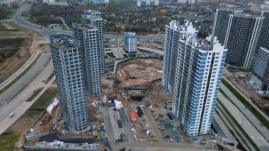 Modern çok katlı binaların yapımı. Yeni bir şehir bloğu inşaatı. İnşaat halindeki binalar ve kule vinçleri. Bulutlu havada hava fotoğrafçılığı.