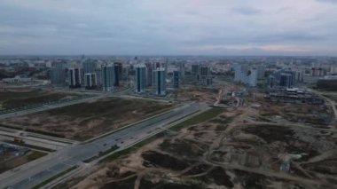 Modern çok katlı binaların yapımı. Yeni bir şehir bloğu inşaatı. İnşaat halindeki binalar ve kule vinçleri. Bulutlu havada hava fotoğrafçılığı.