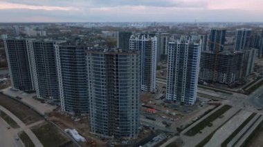 Modern çok katlı binaların yapımı. Yeni bir şehir bloğu inşaatı. İnşaat halindeki binalar ve kule vinçleri. Bulutlu havada hava fotoğrafçılığı.