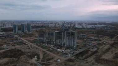 Modern çok katlı binaların yapımı. Yeni bir şehir bloğu inşaatı. İnşaat halindeki binalar ve kule vinçleri. Bulutlu havada hava fotoğrafçılığı.