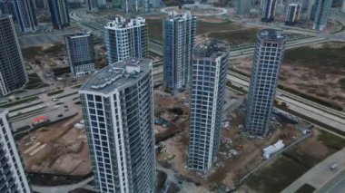 Modern çok katlı binaların yapımı. Yeni bir şehir bloğu inşaatı. İnşaat halindeki binalar ve kule vinçleri. Bulutlu havada hava fotoğrafçılığı.