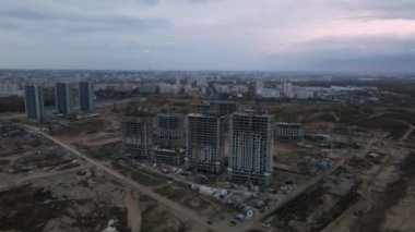 Modern çok katlı binaların yapımı. Yeni bir şehir bloğu inşaatı. İnşaat halindeki binalar ve kule vinçleri. Bulutlu havada hava fotoğrafçılığı.