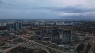 Modern çok katlı binaların yapımı. Yeni bir şehir bloğu inşaatı. İnşaat halindeki binalar ve kule vinçleri. Bulutlu havada hava fotoğrafçılığı.
