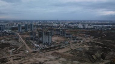 Modern çok katlı binaların yapımı. Yeni bir şehir bloğu inşaatı. İnşaat halindeki binalar ve kule vinçleri. Bulutlu havada hava fotoğrafçılığı.