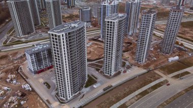 Modern çok katlı binaların yapımı. Yeni bir şehir bloğu inşaatı. İnşaat alanının altındaki binalar. Bulutlu havada hava fotoğrafçılığı.
