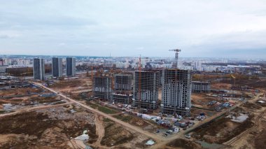 Modern çok katlı binaların yapımı. Yeni bir şehir bloğu inşaatı. İnşaat alanının altındaki binalar. Bulutlu havada hava fotoğrafçılığı.