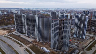 Modern çok katlı binaların yapımı. Yeni bir şehir bloğu inşaatı. İnşaat alanının altındaki binalar. Bulutlu havada hava fotoğrafçılığı.