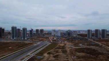 Modern çok katlı binaların yapımı. Yeni bir şehir bloğu inşaatı. İnşaat alanının altındaki binalar. Bulutlu havada hava fotoğrafçılığı.