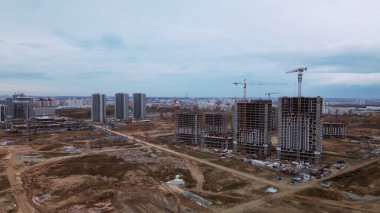 Modern çok katlı binaların yapımı. Yeni bir şehir bloğu inşaatı. İnşaat alanının altındaki binalar. Bulutlu havada hava fotoğrafçılığı.