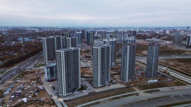 Modern çok katlı binaların yapımı. Yeni bir şehir bloğu inşaatı. İnşaat alanının altındaki binalar. Bulutlu havada hava fotoğrafçılığı.