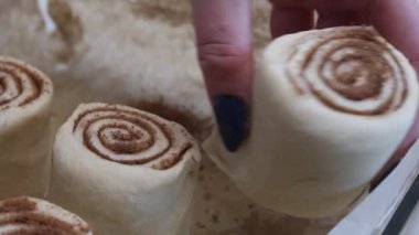 Bir kadın tarçın pişirmek için bir kabın içine dilimlenmiş hamur ve tarçın koyar. Yakın çekim.