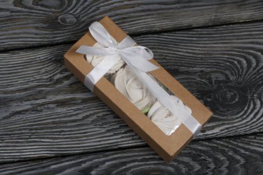 Hediye kutusunda ev yapımı marşmelov. Fiyonka bağlanmış bir kurdeleyle bağlanmış. Siyah çam tahtalarında.