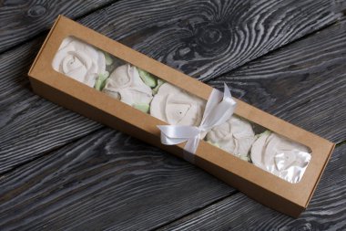 Hediye kutusunda ev yapımı marşmelov. Fiyonka bağlanmış bir kurdeleyle bağlanmış. Siyah çam tahtalarında.