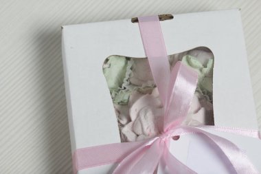 Hediye kutusunda ev yapımı marşmelov. Fiyonka bağlanmış bir kurdeleyle bağlanmış. Siyah çam tahtalarında.