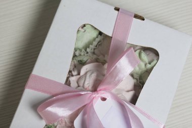 Hediye kutusunda ev yapımı marşmelov. Fiyonka bağlanmış bir kurdeleyle bağlanmış. Siyah çam tahtalarında.