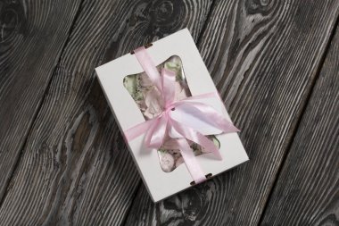 Hediye kutusunda ev yapımı marşmelov. Fiyonka bağlanmış bir kurdeleyle bağlanmış. Siyah çam tahtalarında.