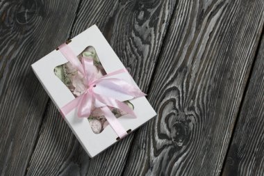 Hediye kutusunda ev yapımı marşmelov. Fiyonka bağlanmış bir kurdeleyle bağlanmış. Siyah çam tahtalarında.