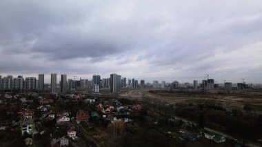 Düşük seviyeli şehir gelişimi. Arka planda, modern çok katlı binaların yapımı devam ediyor. Bulutlu havada çekilmiş. Gökyüzü çok bulutlu. Hava fotoğrafçılığı.