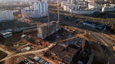 Şehir blokları üzerinde uçuş. Çok katlı binalar ve şantiye. Batan güneşin arka ışığında uçmak. Hava fotoğrafçılığı.