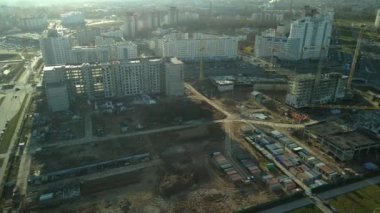 Şehir blokları üzerinde uçuş. Çok katlı binalar ve şantiye. Batan güneşin arka ışığında uçmak. Hava fotoğrafçılığı.