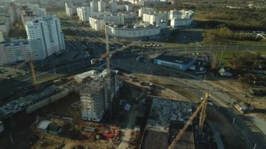 Şehir blokları üzerinde uçuş. Çok katlı binalar ve şantiye. Batan güneşin arka ışığında uçmak. Hava fotoğrafçılığı.