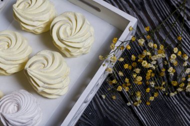 Limon ve zencefilli ev yapımı sarı marşmelov. Siyah çam ağacından yapılmış bir arka plana karşı. Yakınlarda bir çigila dalı var. Yakın çekim..