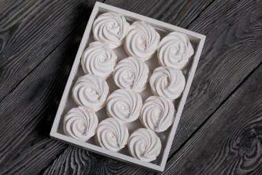 Tepside ev yapımı marşmelov. Pudra şekerli Zephyr, sıra sıra yatıyor. Siyah çam ağaçlarının yüzeyinde.