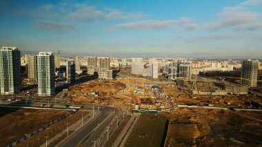 İnşaat alanı. Modern çok katlı binaların yapımı. İnşaat vinçlerinin işi görülebilir. Mavi gökyüzünün arka planına karşı. Hava fotoğrafçılığı.