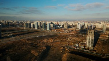 İnşaat alanı. Modern çok katlı binaların yapımı. İnşaat vinçlerinin işi görülebilir. Mavi gökyüzünün arka planına karşı. Hava fotoğrafçılığı.