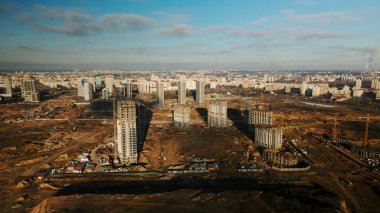 İnşaat alanı. Modern çok katlı binaların yapımı. İnşaat vinçlerinin işi görülebilir. Mavi gökyüzünün arka planına karşı. Hava fotoğrafçılığı.