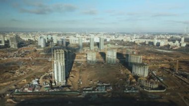 İnşaat alanı. Modern çok katlı binaların yapımı. İnşaat vinçlerinin işi görülebilir. Mavi gökyüzünün arka planına karşı. Hava fotoğrafçılığı.