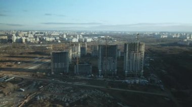 İnşaat alanı. Modern çok katlı binaların yapımı. İnşaat vinçlerinin işi görülebilir. Mavi gökyüzünün arka planına karşı. Hava fotoğrafçılığı.