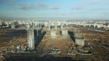 İnşaat alanı. Modern çok katlı binaların yapımı. İnşaat vinçlerinin işi görülebilir. Mavi gökyüzünün arka planına karşı. Hava fotoğrafçılığı.