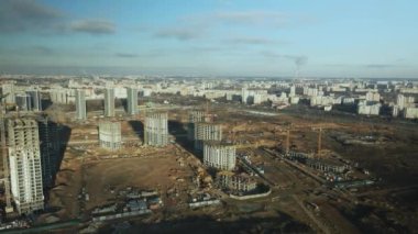 İnşaat alanı. Modern çok katlı binaların yapımı. İnşaat vinçlerinin işi görülebilir. Mavi gökyüzünün arka planına karşı. Hava fotoğrafçılığı.