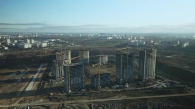 İnşaat alanı. Modern çok katlı binaların yapımı. İnşaat vinçlerinin işi görülebilir. Mavi gökyüzünün arka planına karşı. Hava fotoğrafçılığı.