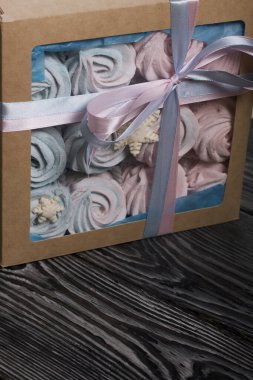 Lokum mavisi ve pembe. El işi ambalajında yatıyor. Mistik kar taneleriyle süslenmiş. Kutu bir kurdeleyle fiyonka bağlanmış. Siyah çam tahtalarında.