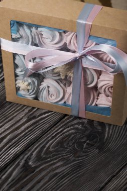 Lokum mavisi ve pembe. El işi ambalajında yatıyor. Mistik kar taneleriyle süslenmiş. Kutu bir kurdeleyle fiyonka bağlanmış. Siyah çam tahtalarında.